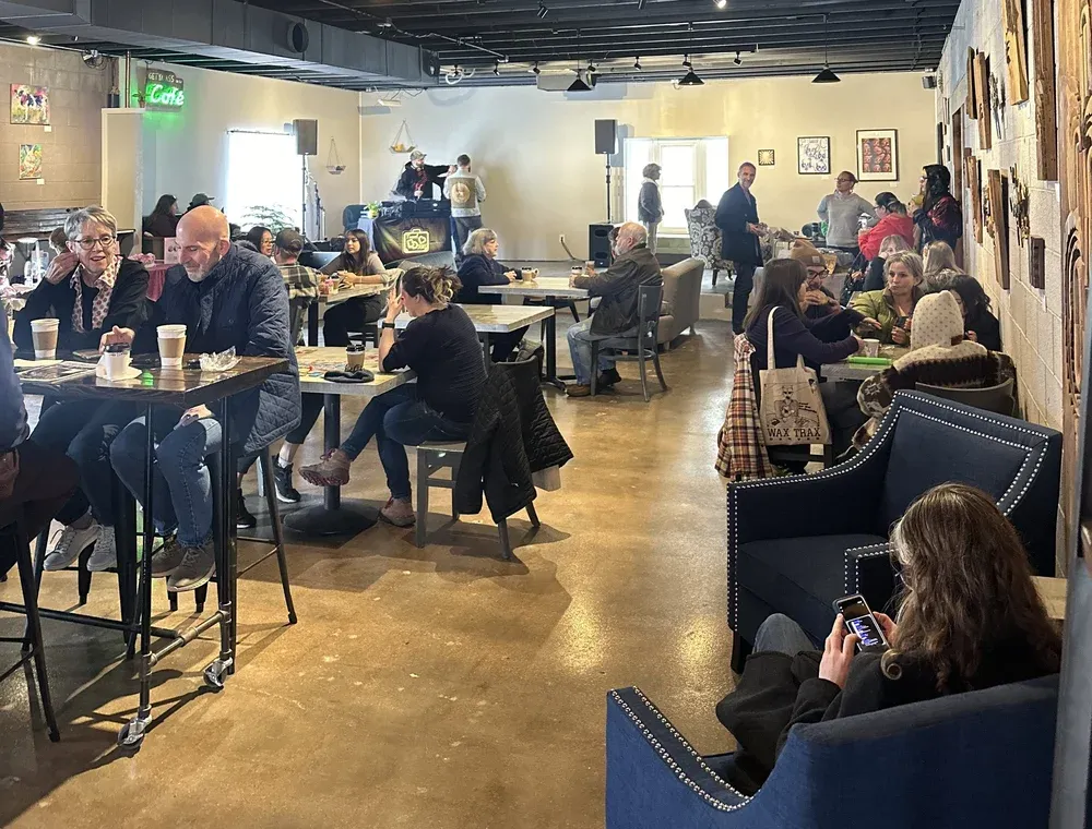 A full house at Mint and Serif during a live event, neighbors at tables under local art